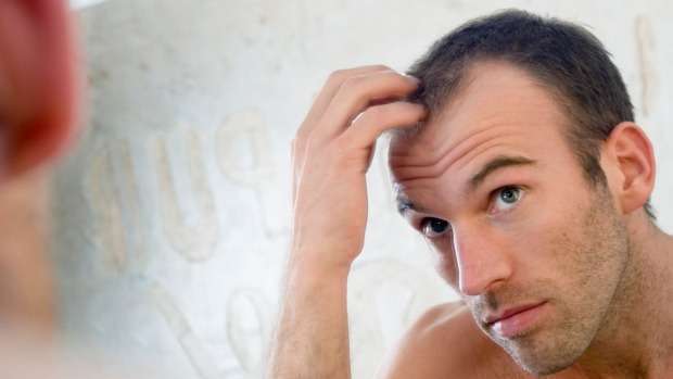 A man checking for hair loss in a mirror