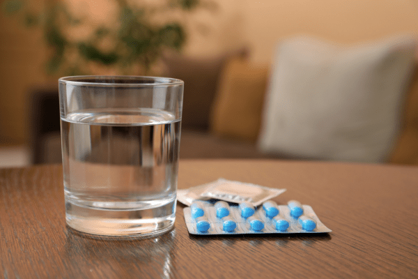 A glass of water and little blue pills