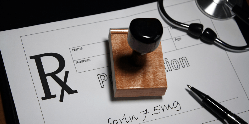A prescription pad and stamp with the word Warfarin on it.