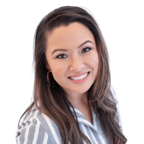 Keilani Perisian-Mason, a woman with long brown hair and hoop earrings, smiles at the camera. She is wearing a white and gray striped shirt, and the background is transparent.
