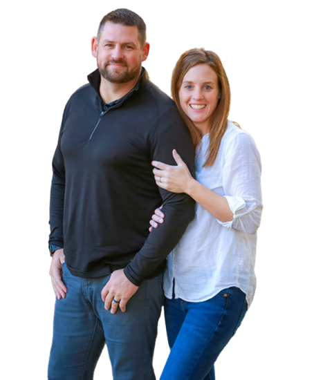 A man in a black long-sleeve shirt and jeans stands next to a woman in a white blouse and blue jeans. The smiling pair, possibly after a chiropractic visit, are looking at the camera with her arm around him.