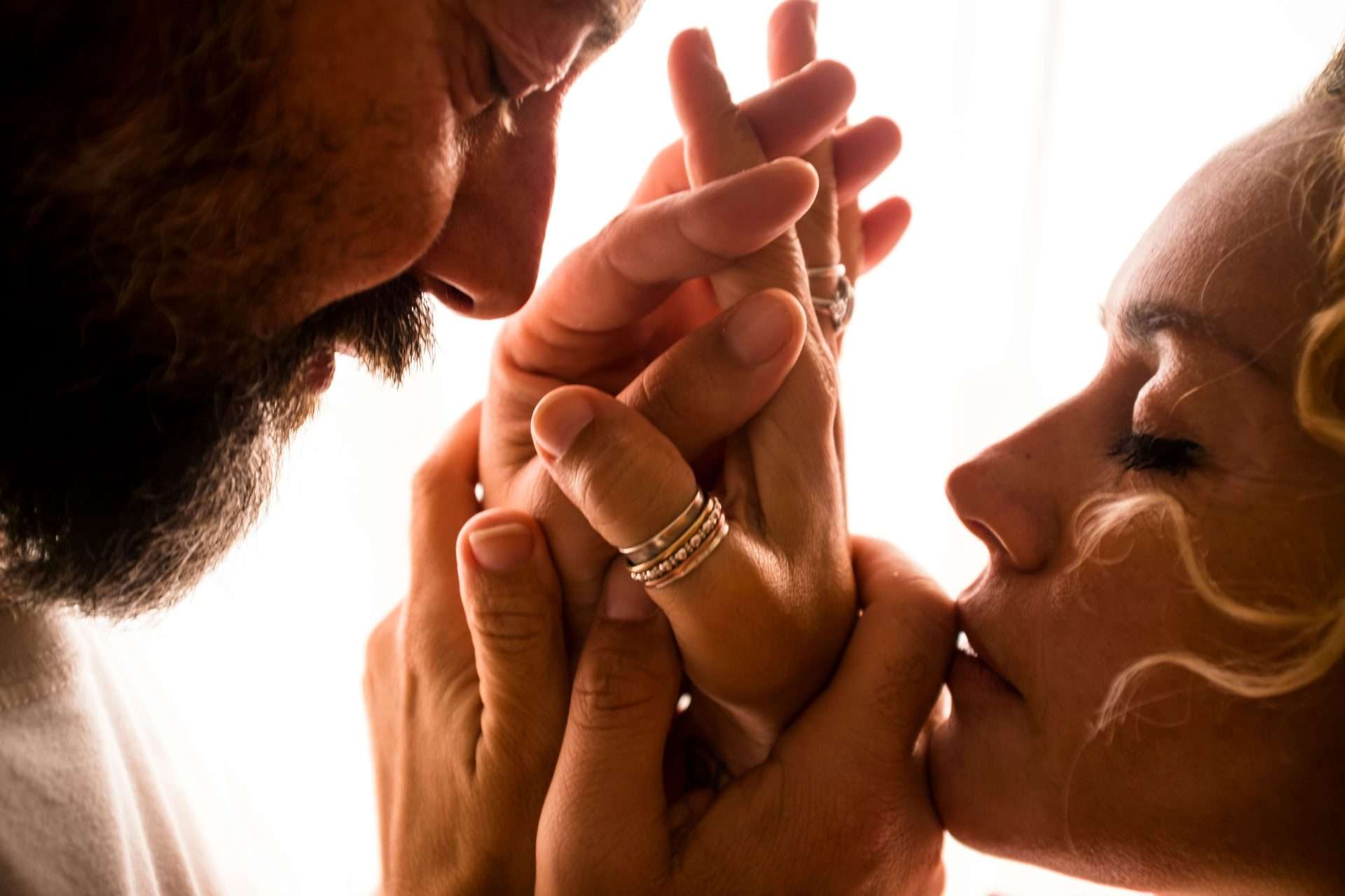 A close up of a man and woman holding hands, faces close