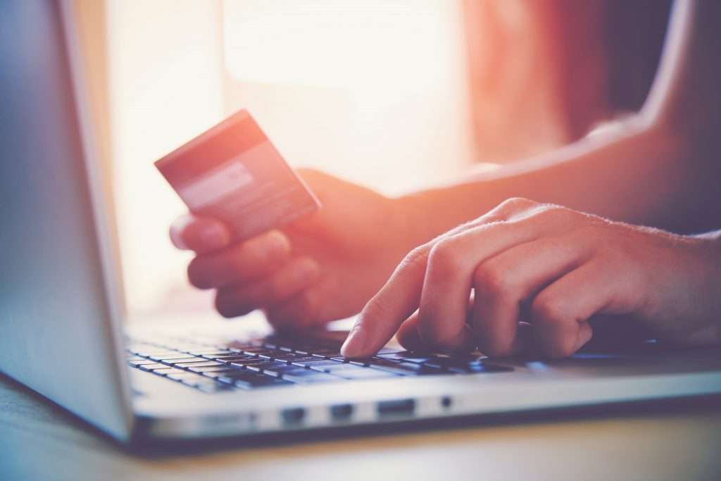 Hands on a laptop holding a credit card