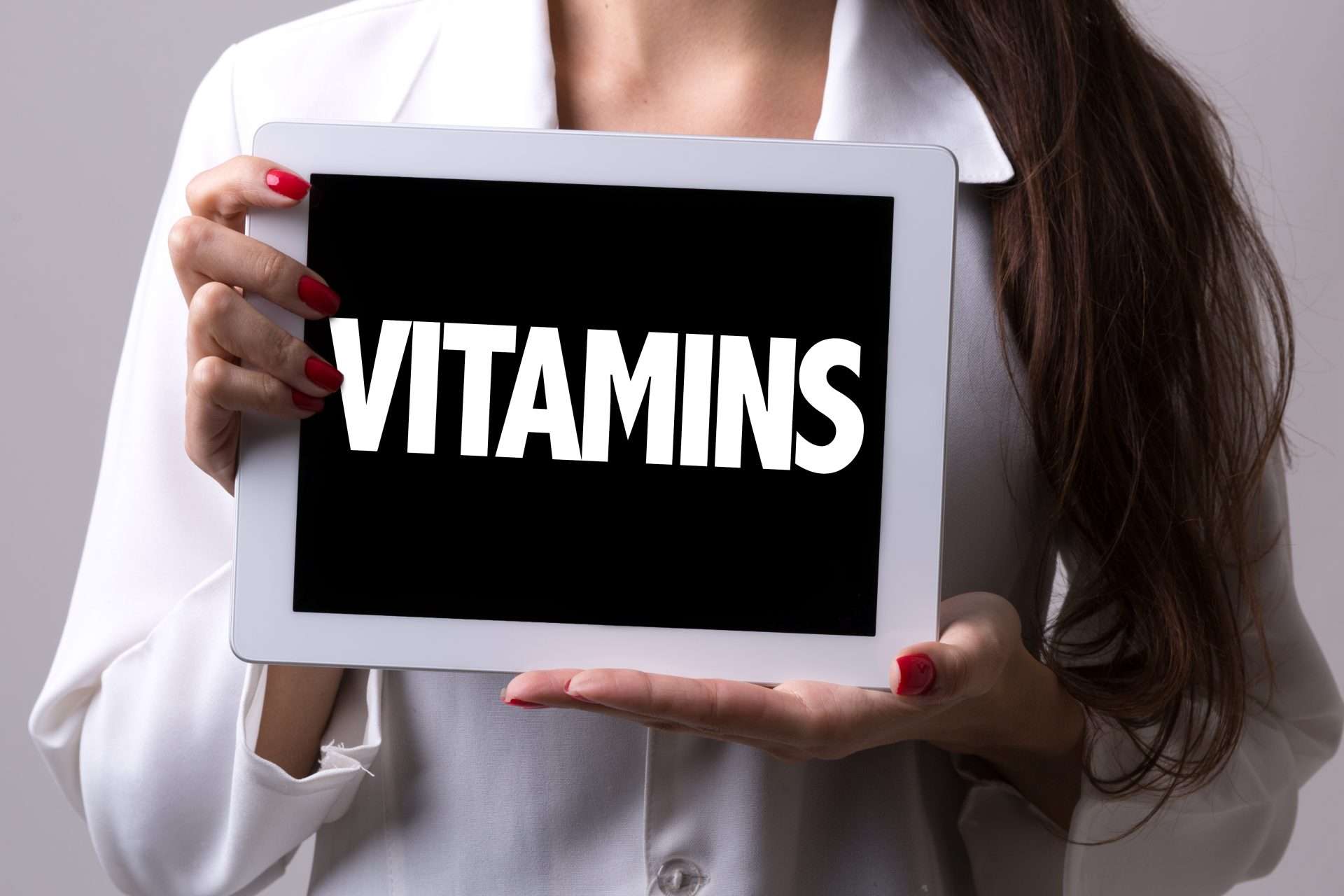 A doctor holding a sign that says "Vitamins"